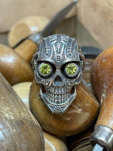 This is Peridot Skull Ring in Sterling Silver with intricate detail, looking like something straight out of Terminator. The Peridot eyes make this piece really pop when sparkling in the light