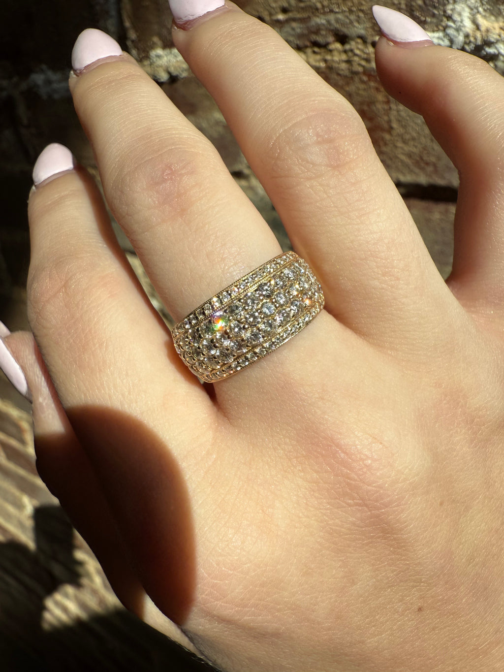 Close-up of a hand wearing a sparkling diamond ring on a wooden surface